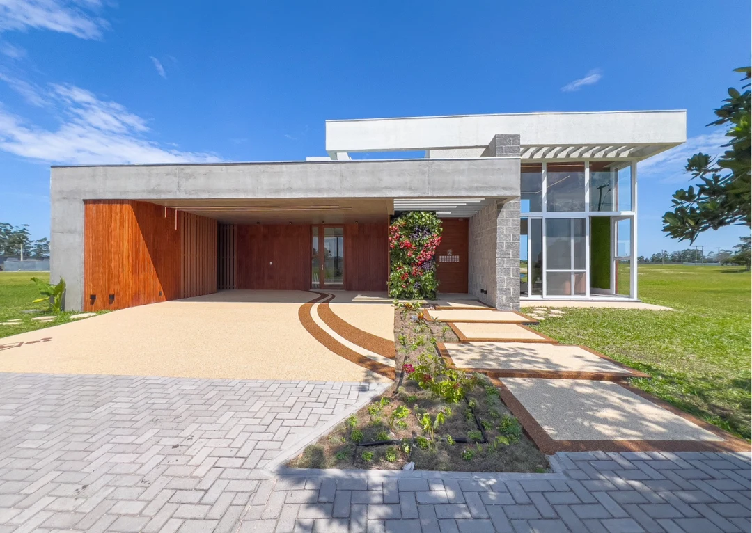 Fachada principal diurna da Casa Carbono Zero, com entrada e jardim vertical